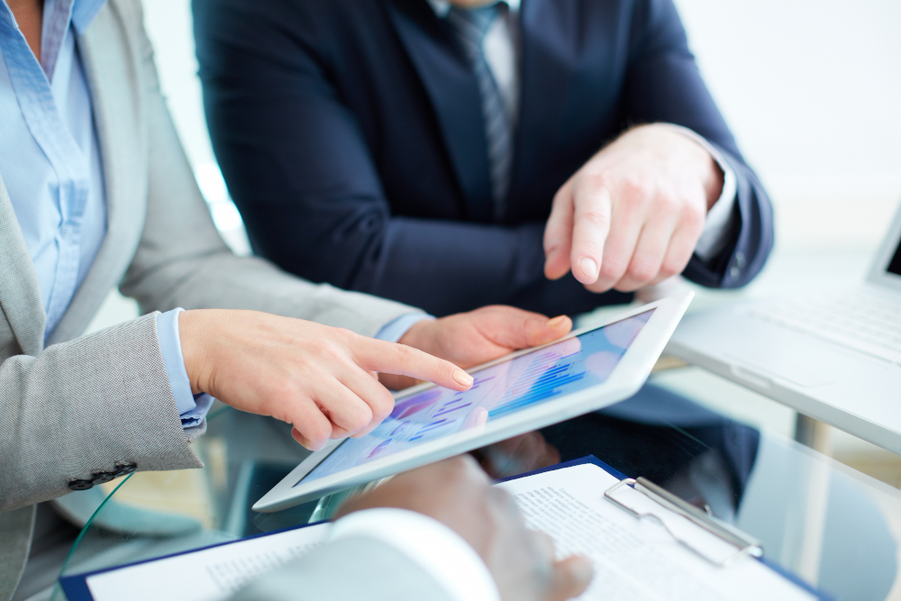 Business professional using tablet to reconcile bank transactions with invoices and receipts